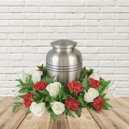 White roses and red carnations arranged around a silver urn