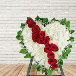 Heart-shaped floral spray with red roses and white flowers on a stand