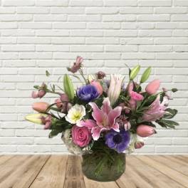 Mixed pink and purple flower arrangement in a glass vase