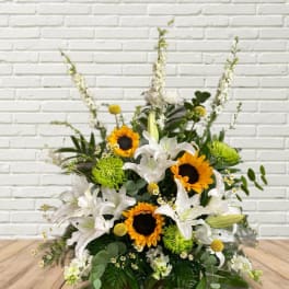 Arrangement of white lilies and sunflowers with green accents
