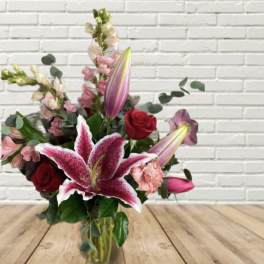 Bouquet of pink lilies and red roses in a glass vase