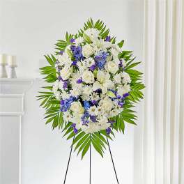Standing floral wreath of white and purple flowers on an easel