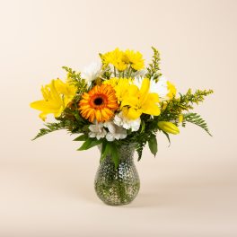 Yellow and white mixed flowers in a clear glass vase
