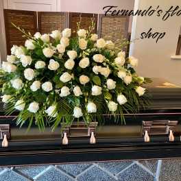 Large white rose casket spray arranged on a dark casket