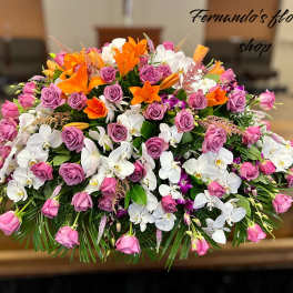 Large casket spray of pink roses, orange lilies, and white orchids.