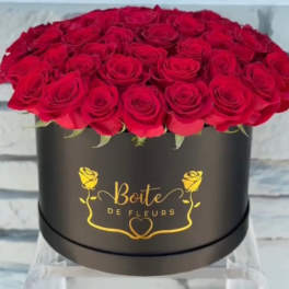 Red roses arranged in a black round box with gold lettering