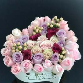 Bouquet of pastel roses and berry sprigs in a white box