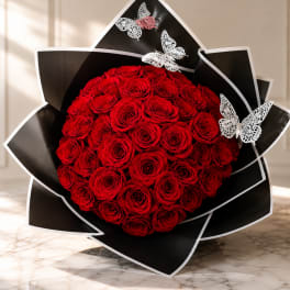 Round bouquet of red roses wrapped in black paper with butterfly accents