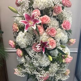 Pink roses and white lilies arranged with white hydrangeas in a standing display
