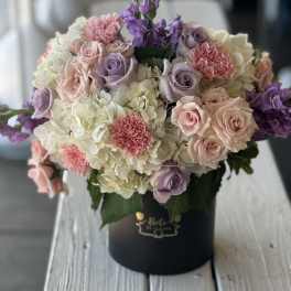 Pastel bouquet of roses, hydrangeas, and purple flowers in a black box