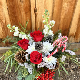 Bouquet of red roses, white flowers, pinecones, and candy canes