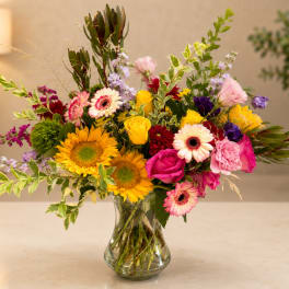 Mixed bouquet of bright flowers in a clear glass vase