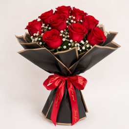 Bouquet of red roses with baby's breath wrapped in black paper and a red ribbon