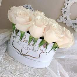 Cream roses arranged in a white hat box with lace fabric