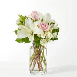 Pink roses and white lilies arranged in a clear glass vase