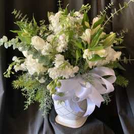 White floral arrangement in a white vase with a satin ribbon