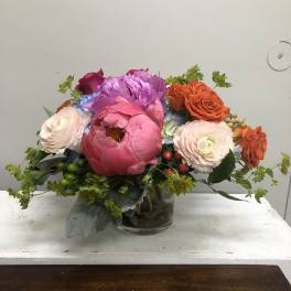 Mixed bouquet of pink, orange, and purple flowers in a glass vase