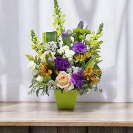 Mixed bouquet in a lime green vase with purple, white, and yellow flowers