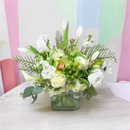 White and green floral arrangement in a square glass vase