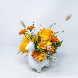 Orange and yellow flower arrangement in a white animal-shaped vase