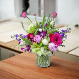 Mixed pink, purple, and white flower arrangement in a clear glass vase