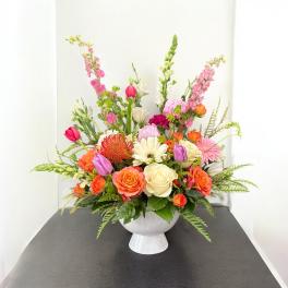 Colorful mixed flower arrangement in a white pedestal vase