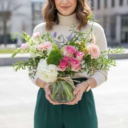 Woman holding a mixed bouquet in a glass vase