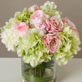 Pink roses and pale green hydrangeas in a clear glass vase