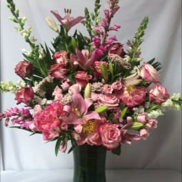 Pink mixed flower arrangement in a tall green vase