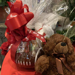 Gift basket with a teddy bear, red ribbon, and wrapped treats