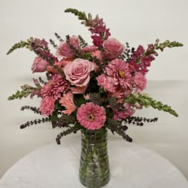 Pink roses and mixed pink flowers in a clear glass vase