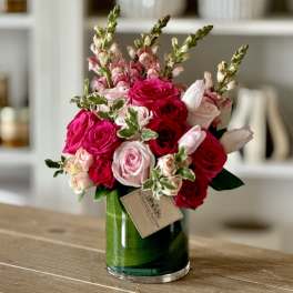 Pink and red rose bouquet in a green glass vase