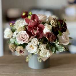 Bouquet of red orchids and pale roses in a gray vase