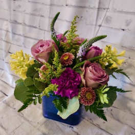 Mixed bouquet of pink roses and purple flowers in a blue vase