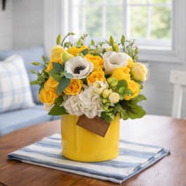 Yellow and white flower arrangement in a yellow vase