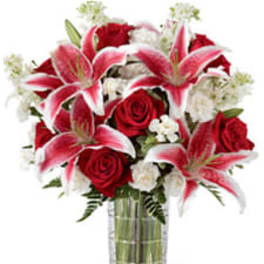 Bouquet of red roses and pink lilies in a clear glass vase