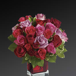 Bouquet of red, pink, and lavender roses in a red glass vase