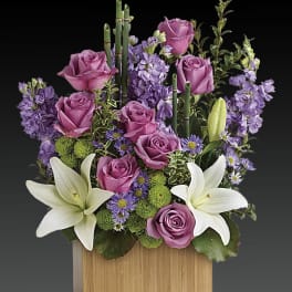 Purple roses and white lilies in a wooden box