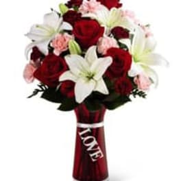 Bouquet of red roses, white lilies, and pink carnations in a red vase