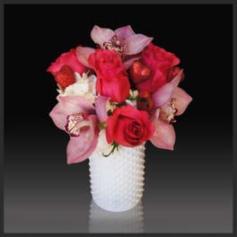 Pink roses and orchids arranged in a white vase