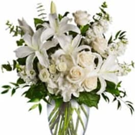 White lilies and roses arranged in a clear glass vase