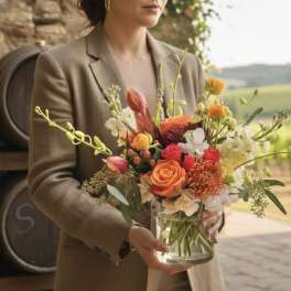 Woman holding a colorful bouquet in a clear glass vase