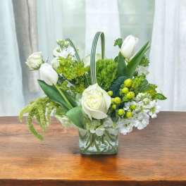 White tulips and roses arranged in a clear glass vase