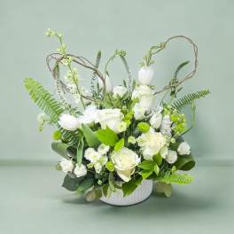White floral arrangement in a white vase with looping twig accents