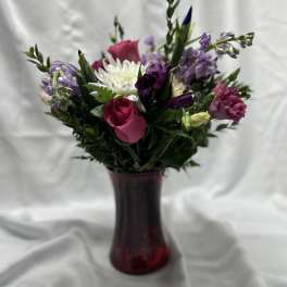Mixed bouquet of pink, white, and purple flowers in a red vase