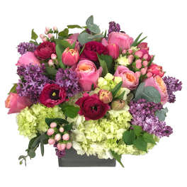 Mixed pink and purple flower arrangement in a rectangular box