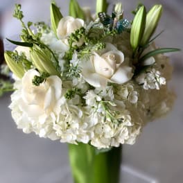 White roses and lilies arranged in a tall glass vase