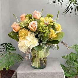 Peach roses and yellow flowers in a glass vase