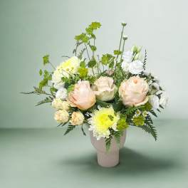 Bouquet of pale peach and white flowers in a pink vase