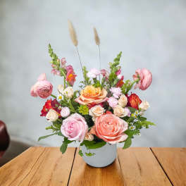 Mixed pink and peach flower arrangement in a white vase